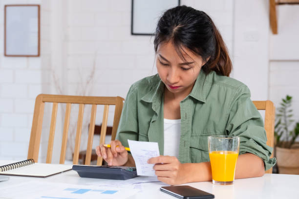 asiatische frau verwenden laptop und taschenrechner berechnen haus budget in der küche zu hause - spreadsheet table banking wealth stock-fotos und bilder