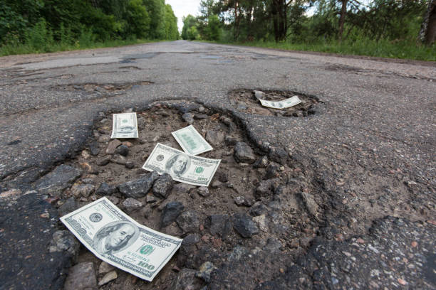 道路上のポットホールでドル紙幣 - money pit ストックフォトと画像