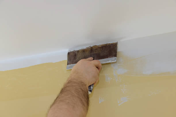 istock Professional builder smooths wall with spatula putty put on leveled surface of wall. 1304478770
