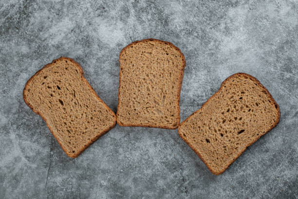 istock Slices of brown fresh bread on a gray background 1304478803