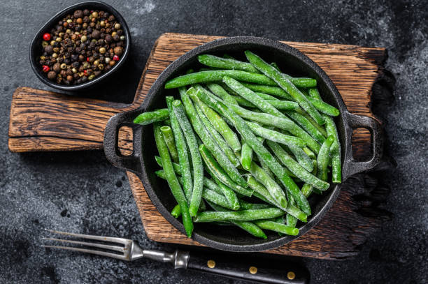 istock Frozen green beans in a pan. Black background. top view 1304483929
