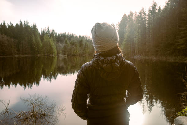 istock Anonymous Young Woman Standing at Winter Lakeshore Looking at View 1304484593