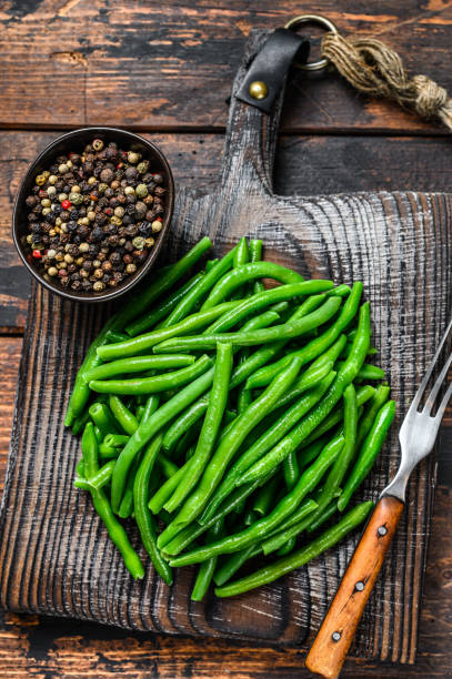 istock Fresh green beans on a cutting board. Dark wooden background. top view 1304484636