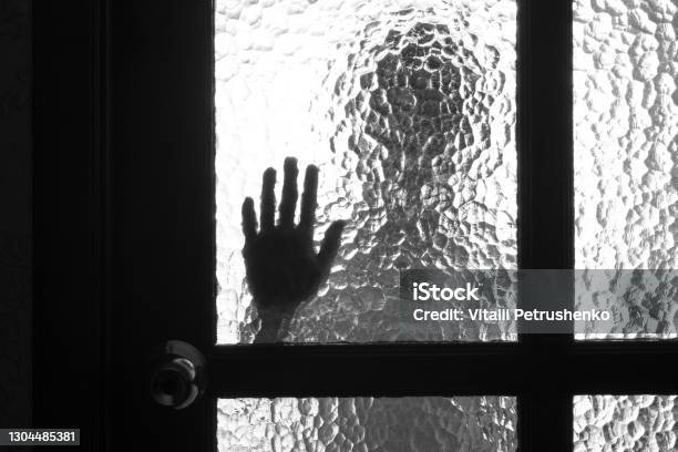 The Silhouette Of The Person And Its Hand Behind The Door With The Textured Glass Stock Photo - Download Image Now