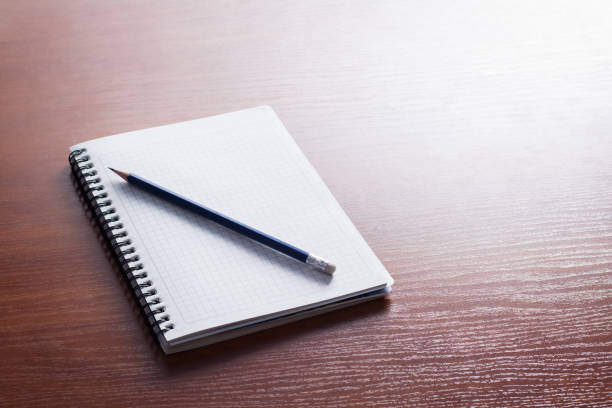 istock Notebook and blue pencil on the wooden table 1304485402