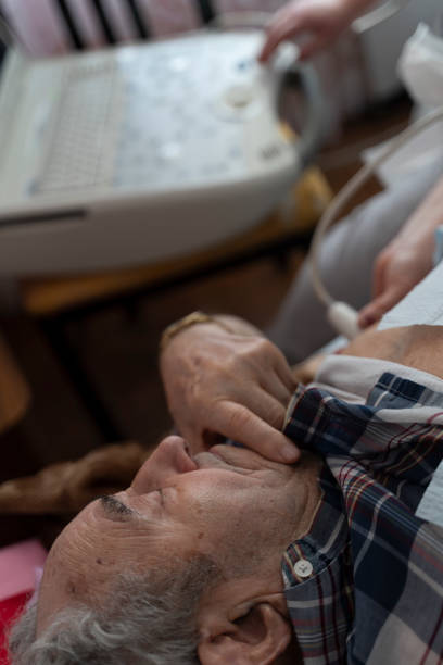 看護師 - 医療技術者は、ポータブル超音波装置を使用して、高齢者97歳の男性患者のための自宅で超音波心臓のヒース検査を行います。 - female 80 plus years vertical people ストックフォトと画像