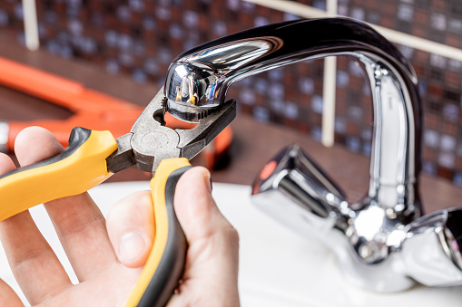 plumbing faucet repair concept. plumber using wrench tool and pliers to adjusting tap leak at bathroom. diy plumber conceptual.