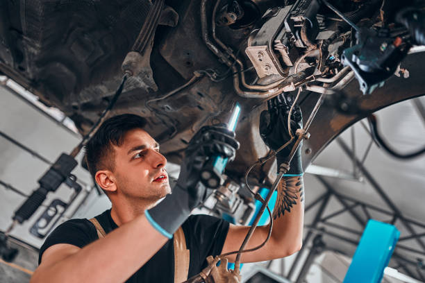 istock Male mechanic with flashlight examining under the car. 1304488705