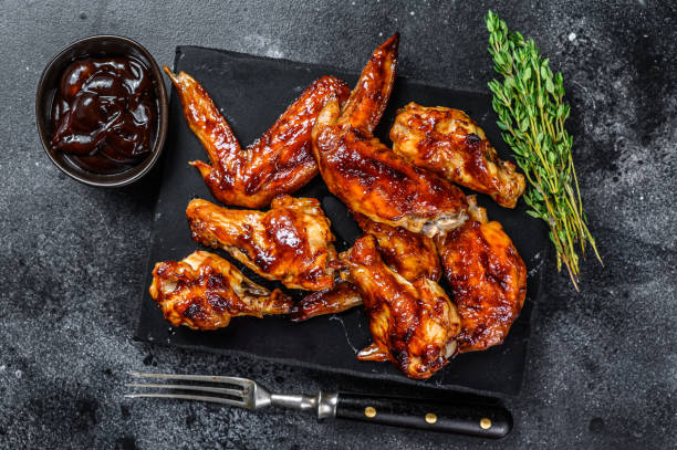 Hot Barbecue chicken wings with sauce bbq. Black background. Top view