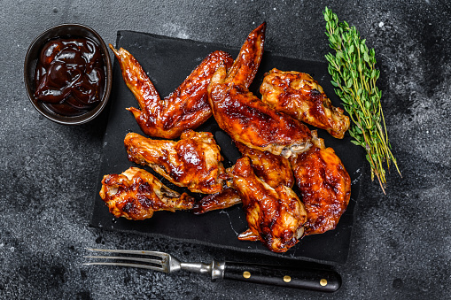 Hot Barbecue chicken wings with sauce bbq. Black background. Top view.