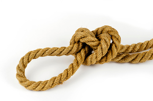 Hemp rope with tied knot in close-up on white background. Coil of rope. Selective focus.