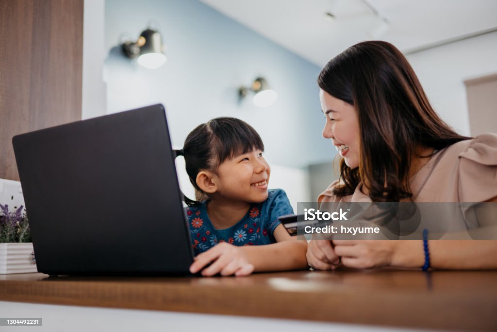 Ung asiatisk mamma och dotter online shopping med bärbar dator och kreditkort - Royaltyfri Kreditkort Bildbanksbilder Ung asiatisk mamma och dotter online shopping med bärbar dator och kreditkort - Royaltyfri Kreditkort Bildbanksbilder