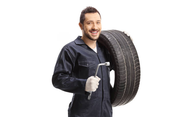istock Auto mechanic holding a tire and a lug wrench 1304493108