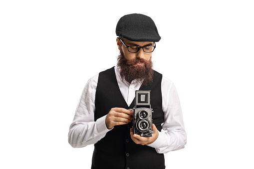 Bearded man recording with a vintage camera isolated on white background