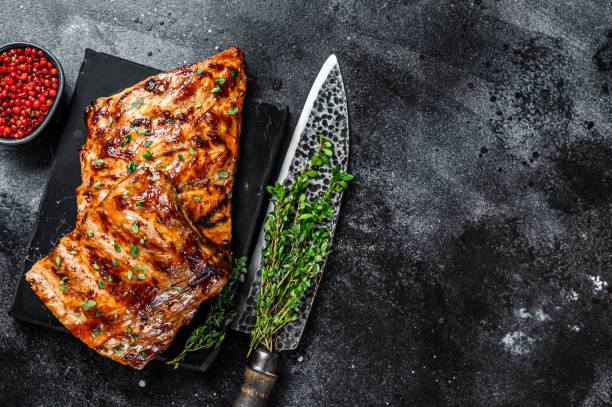 istock Barbecue pork rack spare ribs on a marble board. Black background. Top view. Copy space 1304494542