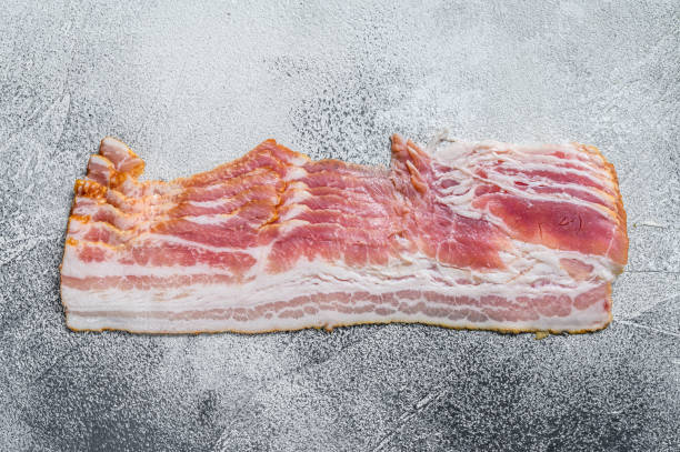 istock Smoked sliced pork bacon ready for cooking. White background. Top view 1304495532