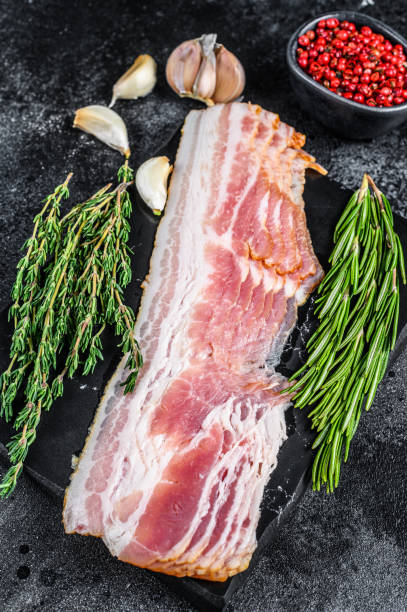 istock Raw sliced pork bacon ready for cooking. Black background. Top view 1304495930