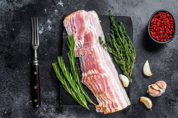 istock Raw sliced pork bacon ready for cooking. Black background. Top view 1304495950