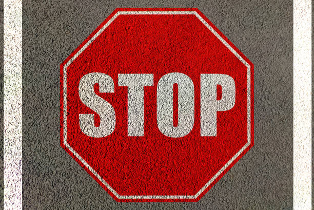 istock Stop icon in red painted on road lane  , text is stop traffic movement 1304496173