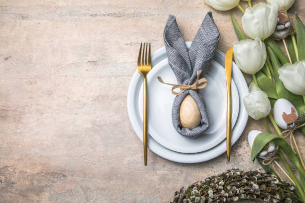 Easter holiday table setting with bunny  from egg on white plate and tulips flowers.  Gray concrete table, top view with copy space for text. Happy Easter background stock photo