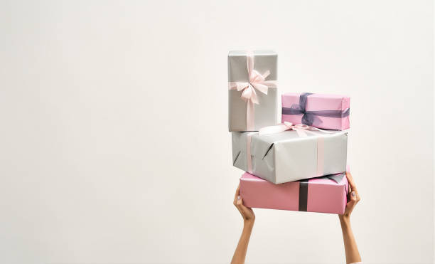 istock Female hands holding stack of wrapped colorful gift boxes over the head against light background, copy space for text 1304498870