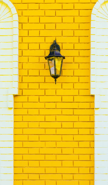 istock Decor element on symmetrical building facade with lamp, vintage retro lantern on yellow trendy white brick wall with texture, loft style architectural decorative background 1304500066