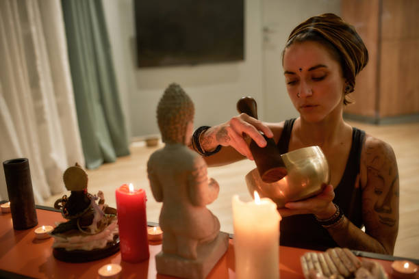 istock Serious young woman playing singing bowl beside altar 1304500255
