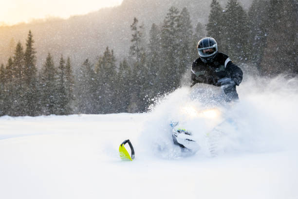 istock Man having fun speeding with a snowmobile through the powder snow at sunset 1304500506