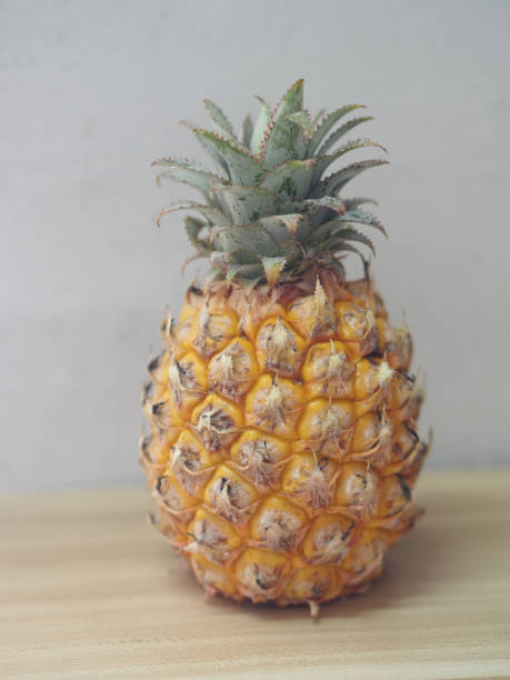 istock pine apple on wooden table, yellow sweet fruit 1304500514