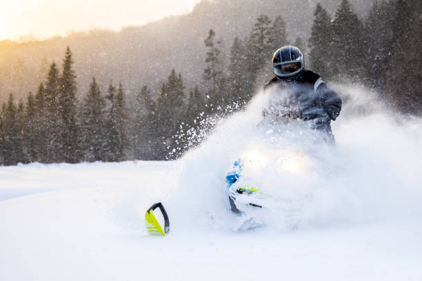 istock Man having fun speeding with a snowmobile through the powder snow at sunset 1304500554