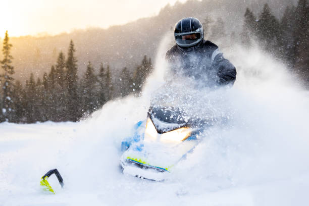 hombre divirtiéndose a toda velocidad con una moto de nieve a través de la nieve polvo al atardecer - laurentian moutains fotografías e imágenes de stock