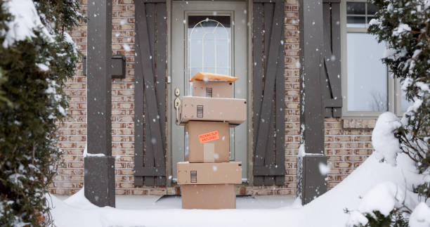 haufen angelieferter boxen wird während des schneesturms im winter vor der haustür stehen gelassen - blizzard house storm snow stock-fotos und bilder