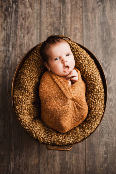 3. мальчик в коричневой обертке зевает на новорожденной фотосессии - baby animal nest newborn lying down стоковые фото и изображения