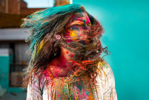 Happy Indian young woman playing with color powder and celebrating the Holi festival.