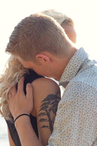 istock Young Man Caring and Embracing Woman At Beach 1304501500