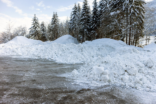 Big piles of snow from plowing on a road.