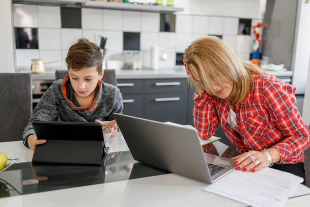 istock Desperate business woman using laptop and sitting by a boy using digital tablet 1304504359