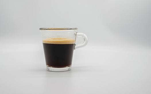 Close up of a glass of espresso isolated on white background. Side view