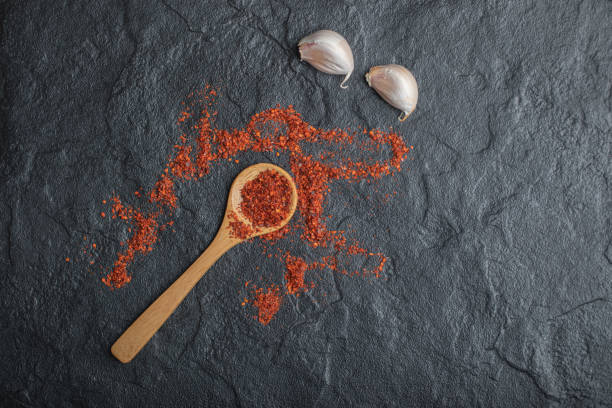 istock Red peppercorns with garlic on black background 1304508941