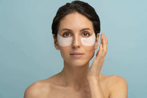 Woman applying hydrogel under-eye recovery patches enriched with collagen, vitamin E. Face skincare Woman applying hydrogel under-eye recovery patches enriched with collagen, vitamin E, provides intensive hydration and diminishes the signs of aging, helps reduse eye puffiness. Face skincare beauty. one eyed stock pictures, royalty-free photos & images