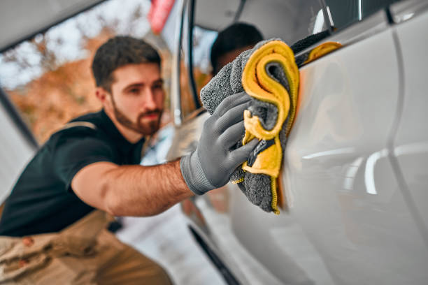 mann nach dem waschen wischt weißes auto mit einem lappen bei autowäsche. - mechanic auto repair shop manual worker men stock-fotos und bilder