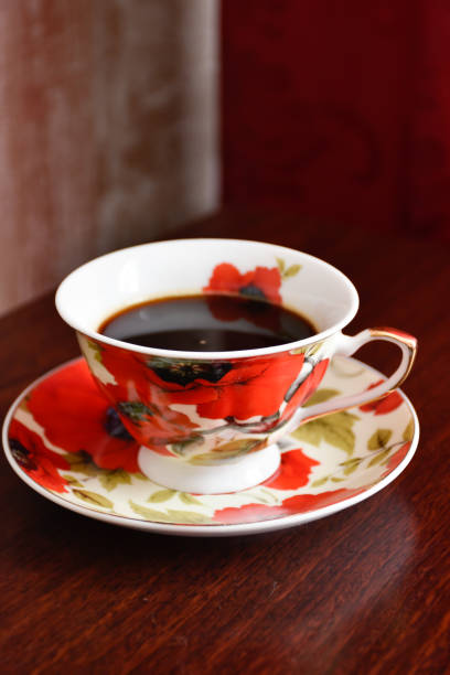 A cup of coffee on a saucer with poppies.
