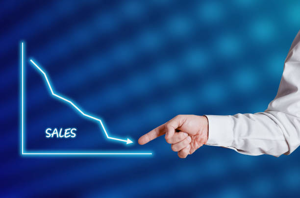 istock Businessman hand points to the word sales with a decreasing chart or graph. 1304509621