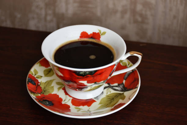 Cup of black coffee on the saucer with red poppies.