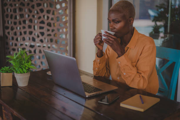 istock black adult woman drinks coffee while working on her computer in a coffee shop focus on the face 1304514072