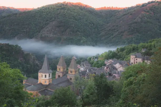 Hillside view of the quaint and charming medieval French village of Conques, Aveyron, a popular summer tourist destination in the Occitanie region of France.