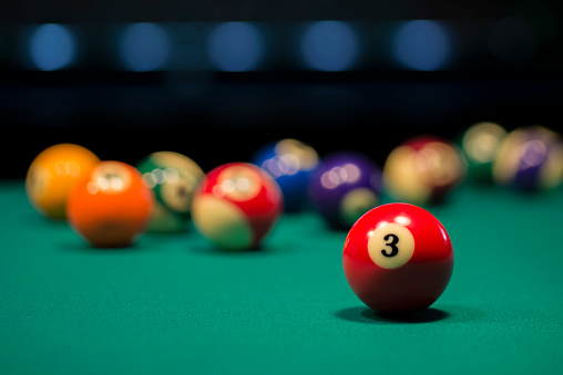 Teenage boy learning to play snooker (billard) at a pub.\nShot with Canon R5