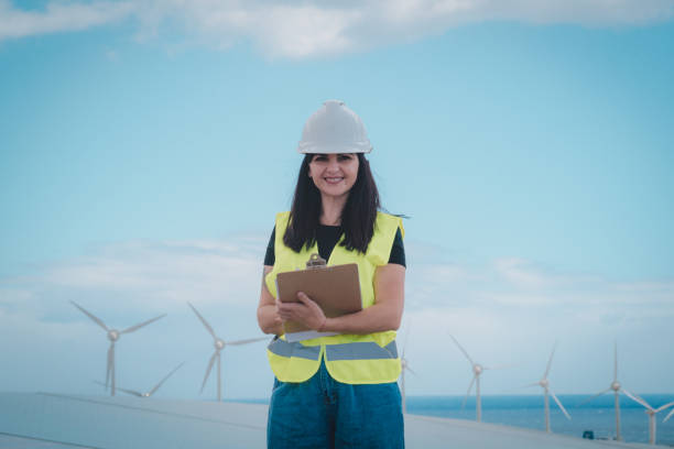 adult female engineer supervises solar panels and windmills in a renewable energy complex stock photo