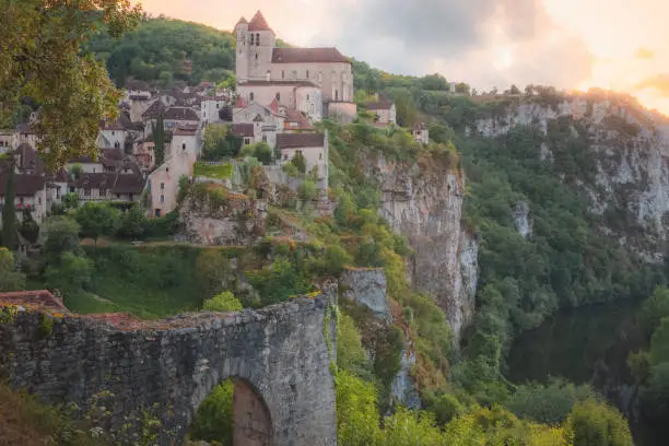 Sunset or sunrise view of the scenic hilltop medieval French village of Saint-Cirq-Lapopie, France with the fortified church illuminated above the Lot River wi