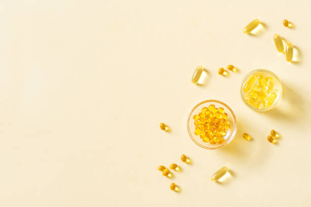 Oil filled capsules (softgel) Oil filled capsules (softgel) of food supplements: fish oil, omega 3, omega 6, omega 9, vitamin A, vitamin D3, vitamin E, evening primrose oil, borage oil. Yellow softgels, top view, copy space. vitamin a nutrient stock pictures, royalty-free photos & images